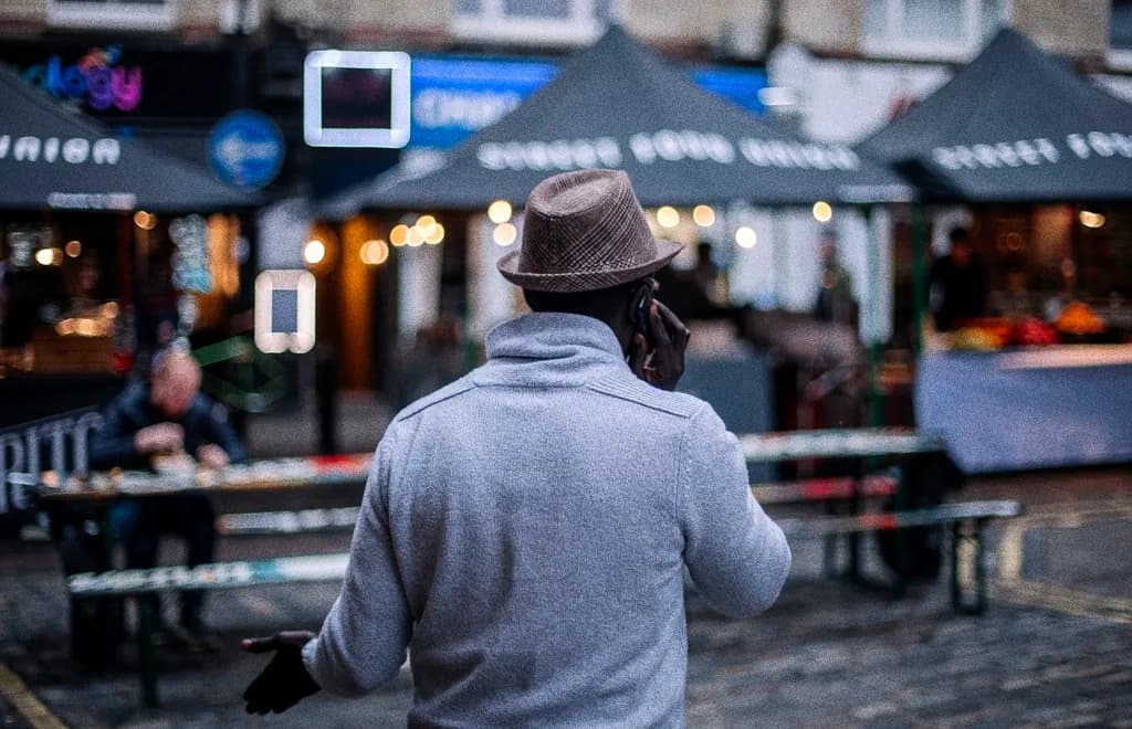 A person in a hoodie walking past night market food stalls