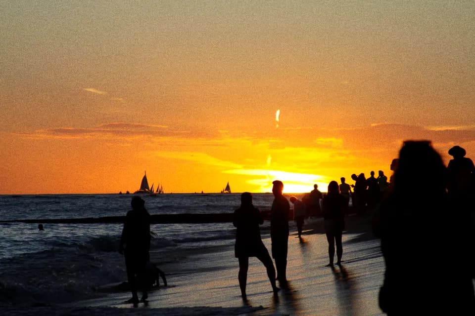 People scattered along a shoreline at dusk